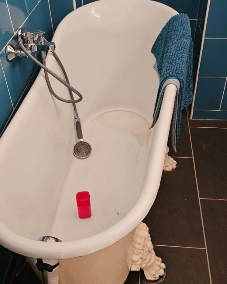 Baignoire ancienne à pieds de lion dans une salle de bains carrelée de bleu