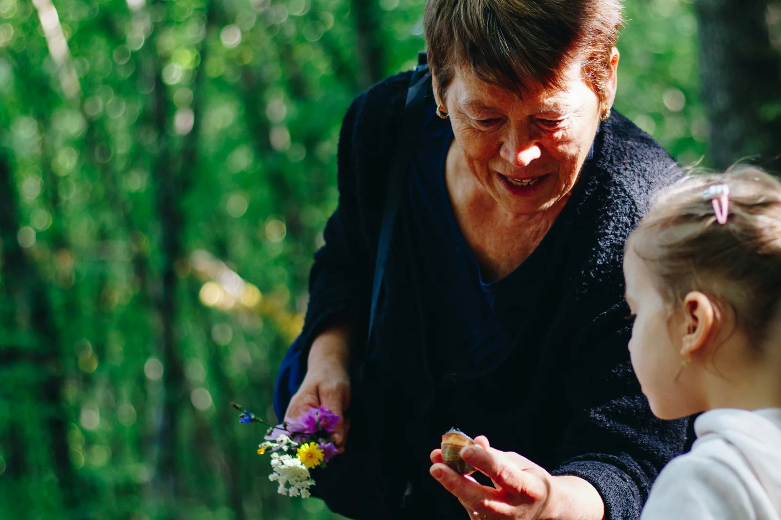 Une grand-mère montre un coquillage à sa petite-fille lors d'une promenade en forêt