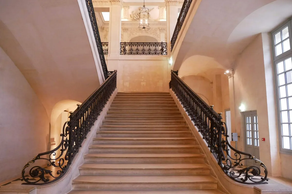 Escalier de pierre à rampes en fer forgé dans un immeuble ancien