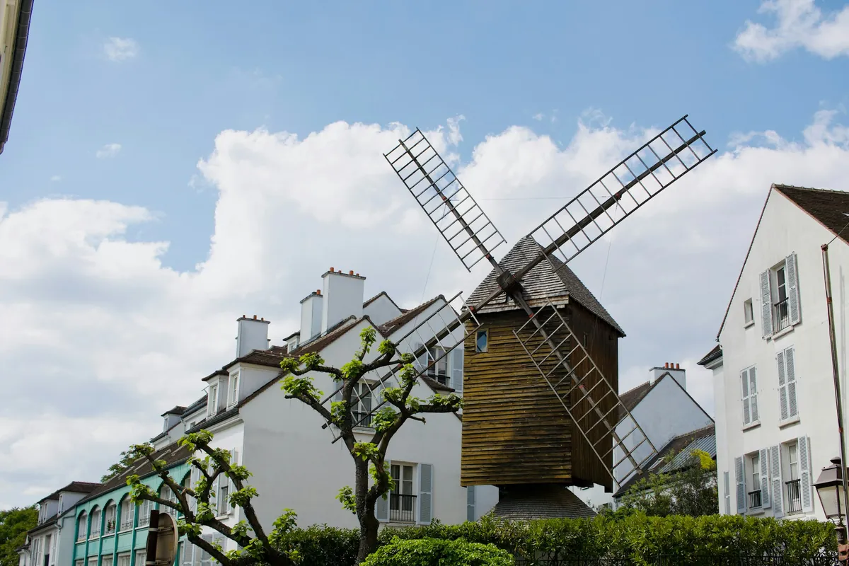 Moulin à vent en bois entre des immeubles clairs