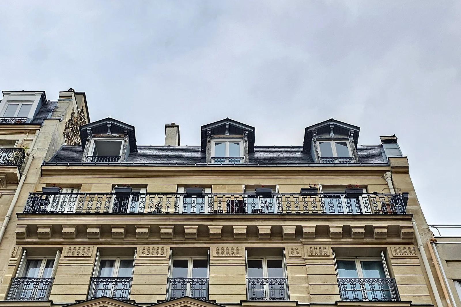 Dernier étage d'un immeuble en pierre de taille, lucarnes et balcon filant