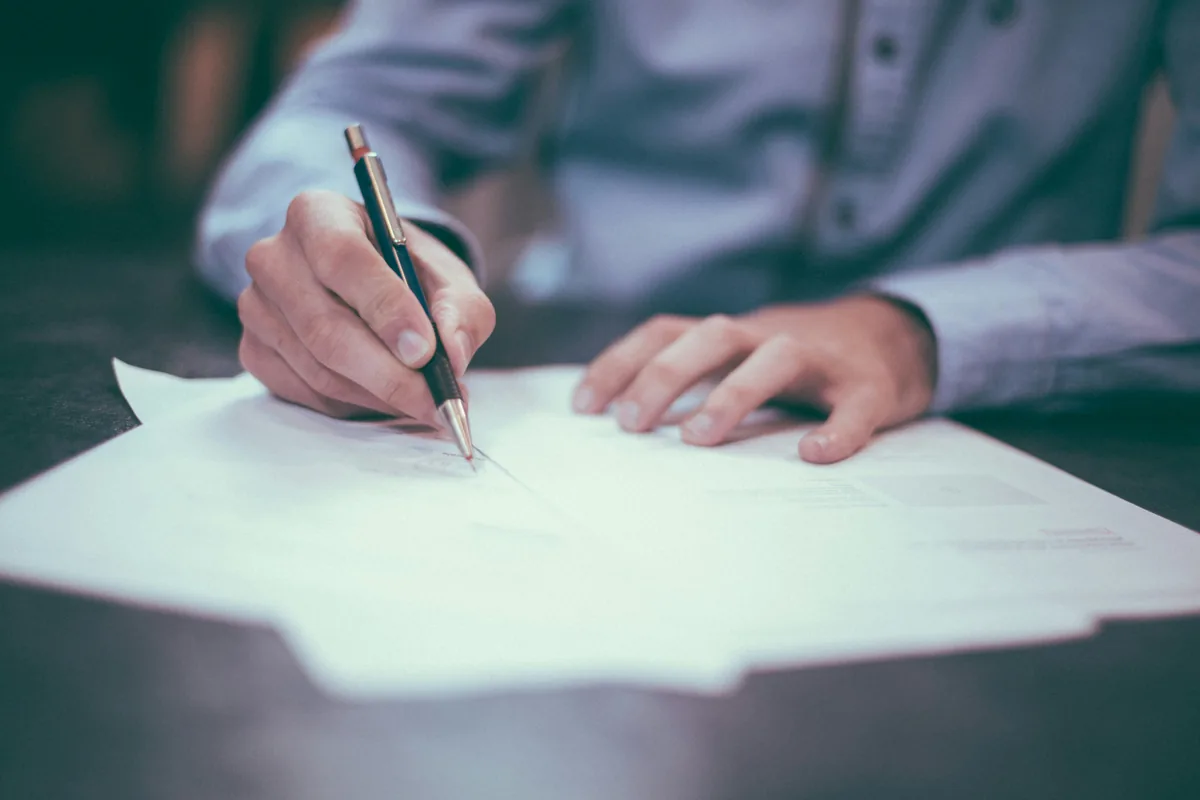 Une main signe un document posé sur un bureau