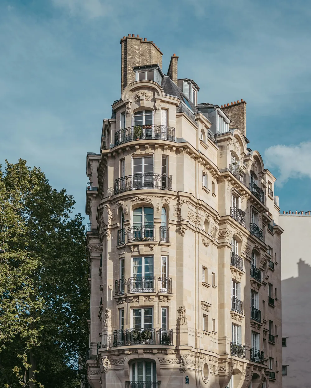 Immeuble de pierre ouvragée, arbres et ciel bleu
