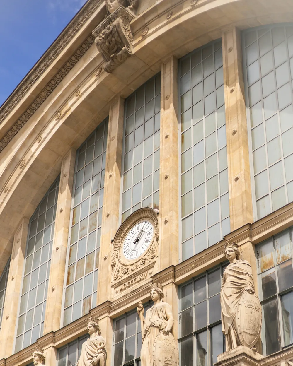 Façade de gare en pierre, horloge et statues