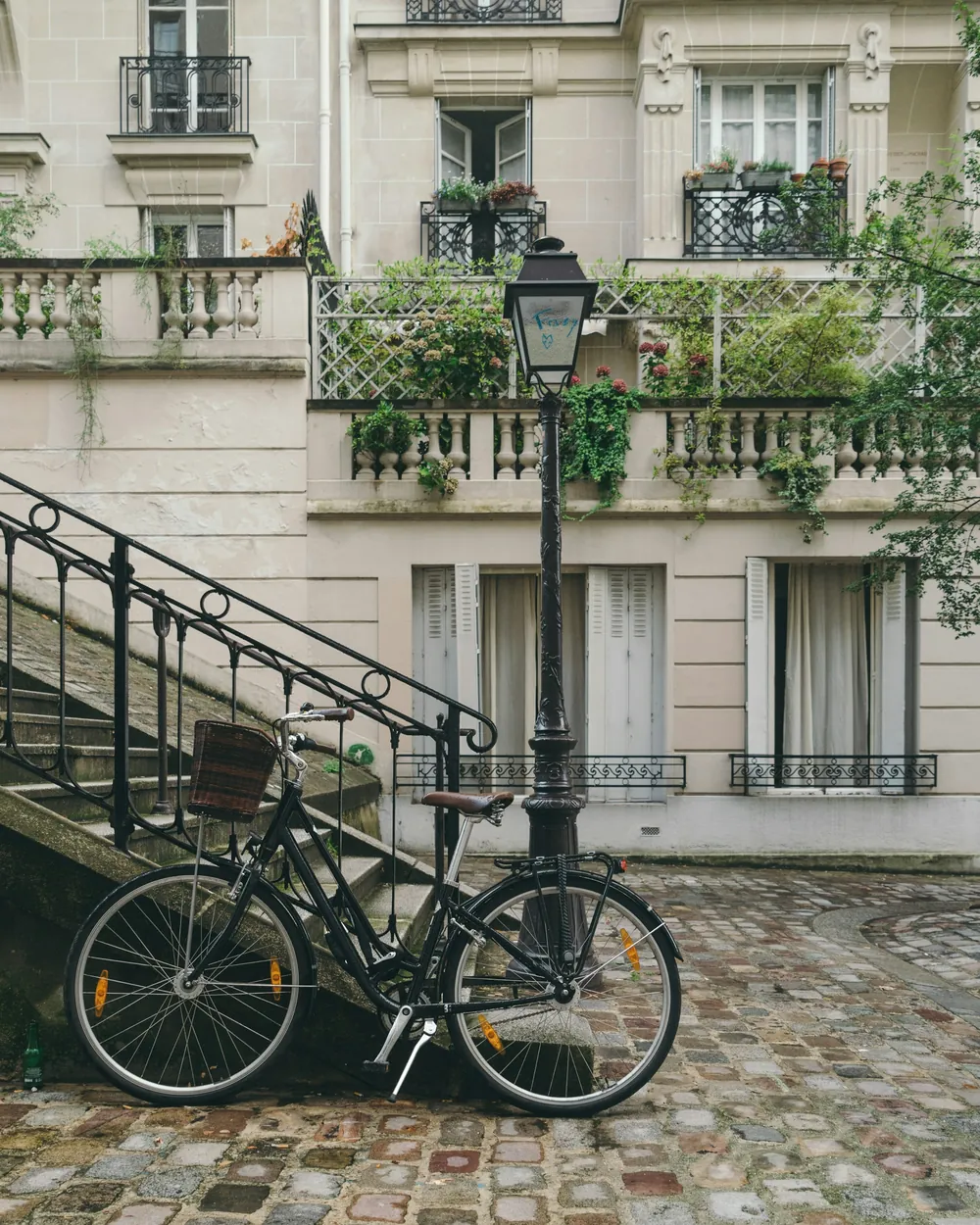 Vélo contre un réverbère devant une façade fleurie